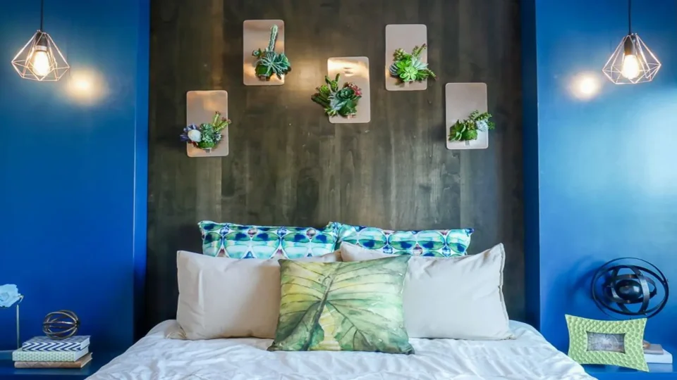 a blue bedroom with a headboard and plants on the wall at The Biltmore at  Park