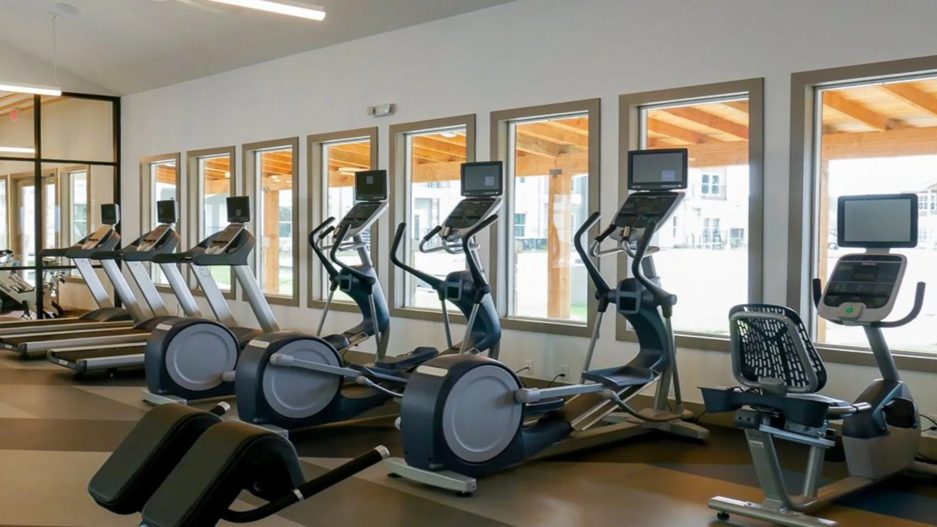 a gym with tread machines and windows at The Biltmore at  Park